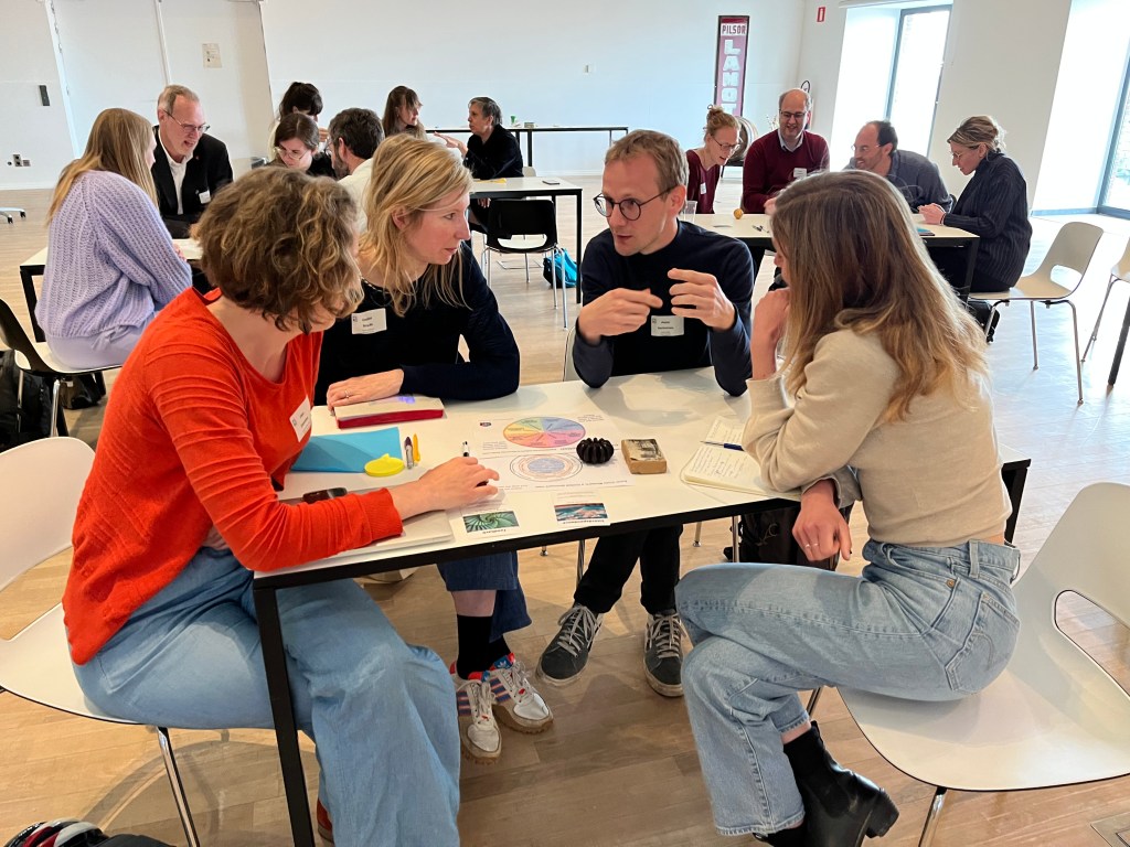 Training session that Climate Museum UK delivered in Mechelen, Brussels. People are sitting around tables, discussing with handling objects and handouts. 